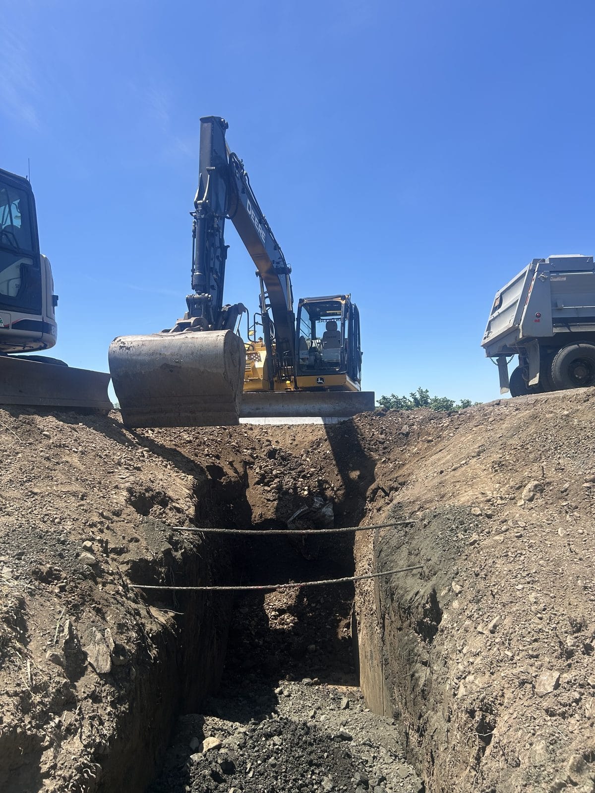 Excavator working a deep trench with the dump truck alongside